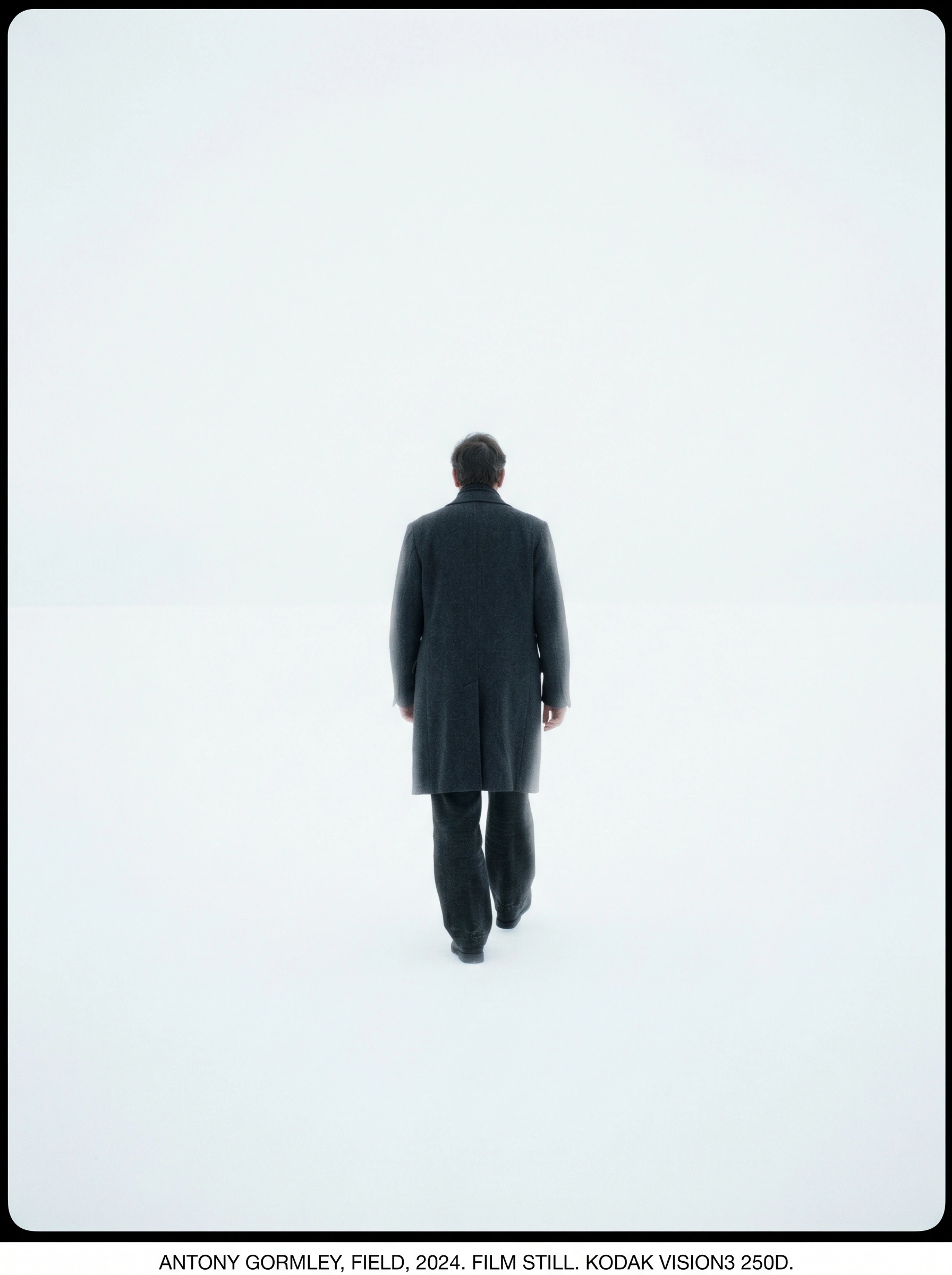 Small figure in a charcoal wool overcoat walking directly away across a featureless white expanse, the horizon dissolving into fog. Black border and typed caption referencing Antony Gormley and Kodak Vision3 250D, austere conceptual frame with Bressonian solitude and quiet dread.