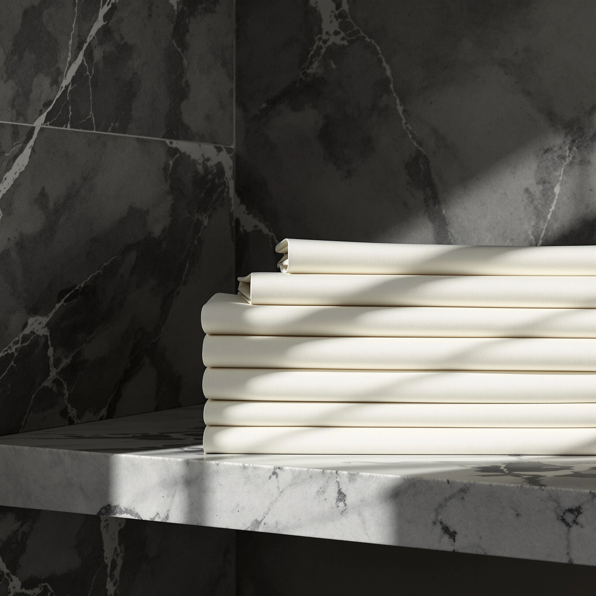 Stack of crisply folded bone-white sheets resting on a veined marble shelf, set against a charcoal marble wall. Hard side light defines every fold edge and pulls long diagonal shadows across the linen. Luxury hospitality still life, high-contrast monochrome composition.