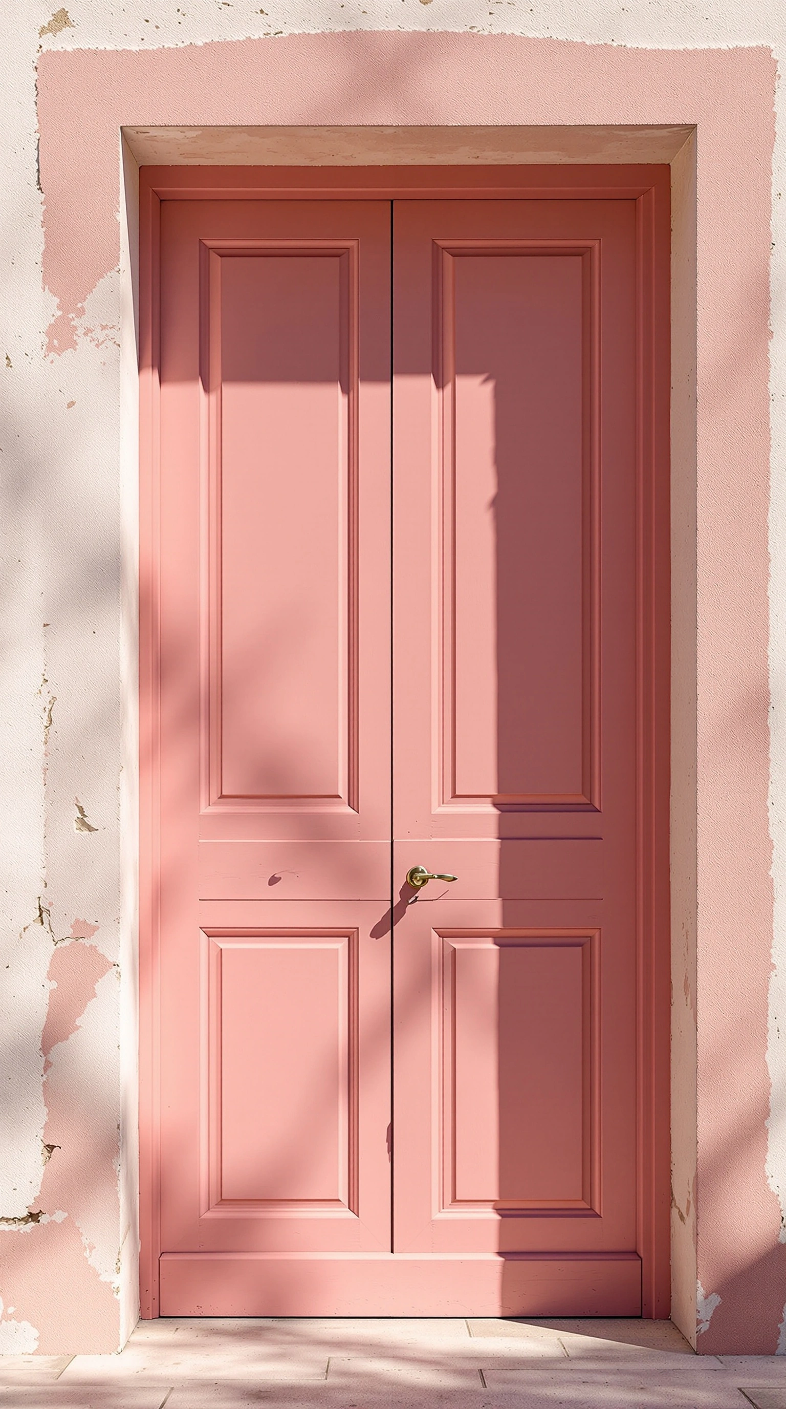 A tall paneled door in chalky dusty-rose set into a sun-bleached limestone facade, brass lever catching a glint of noon. Hard Mediterranean sunlight carves a crisp diagonal shadow across the pale wall, exposing scraped plaster at the edges. Frontal symmetry, color-block composition, mid-format chroma.