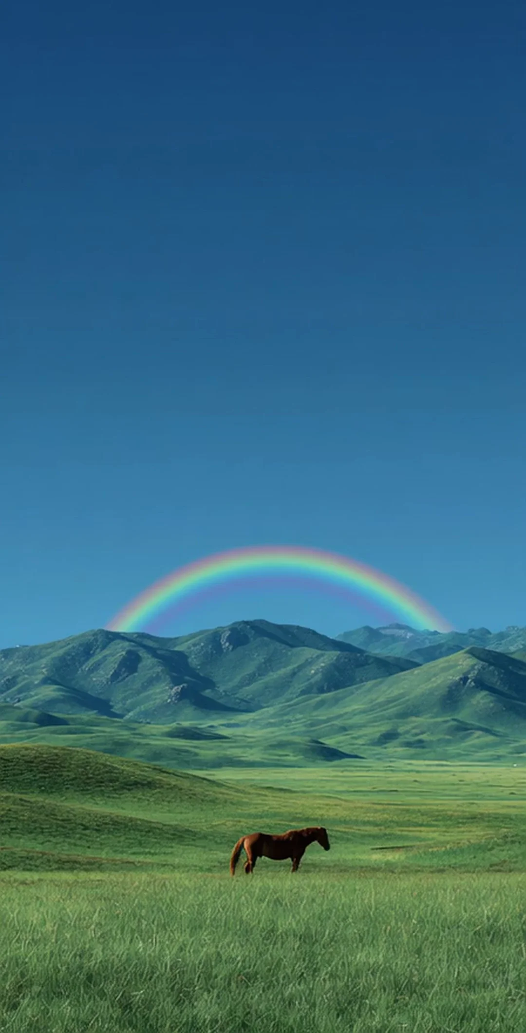 A lone chestnut horse grazes on a vast emerald Mongolian steppe under a deep blue sky, a perfect rainbow arching over distant green mountains. Wide tranquil landscape, painterly stillness. Motion: horse swings tail and lowers head, grass ripples in breeze, rainbow shimmers softly.